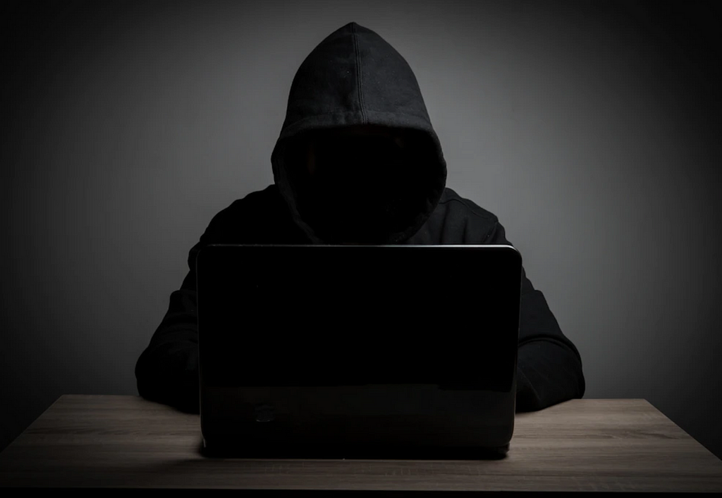 A hooded man wearing a black hoodie using a laptop. #hackers #hacking #cybersecurity #awareness #passwords #passwordmanager 11 Tips to Avoid Getting Hacked — by Jonse Teopiz