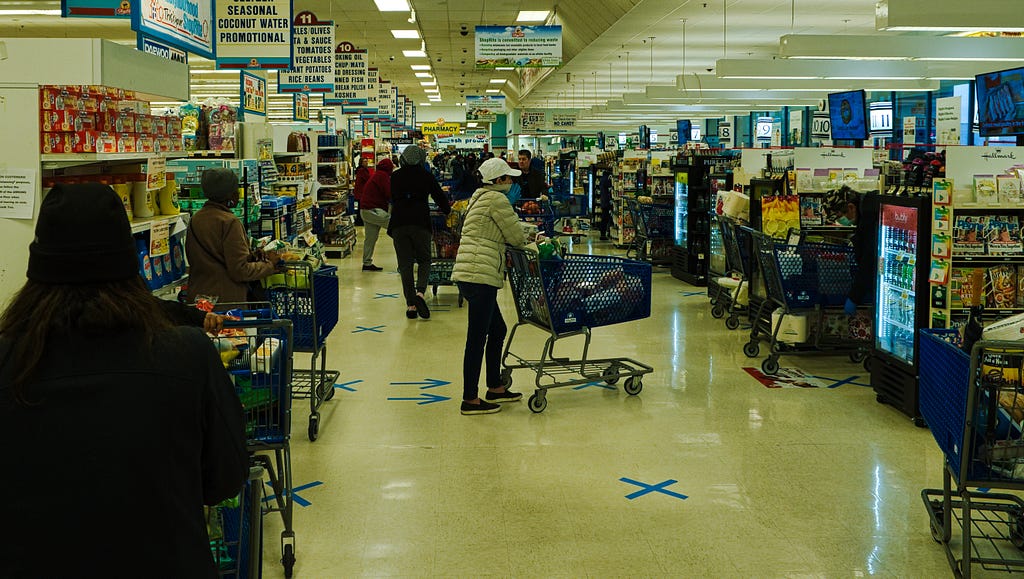 Customers wait in lines at grocery store during COVID-19 pandemic.
