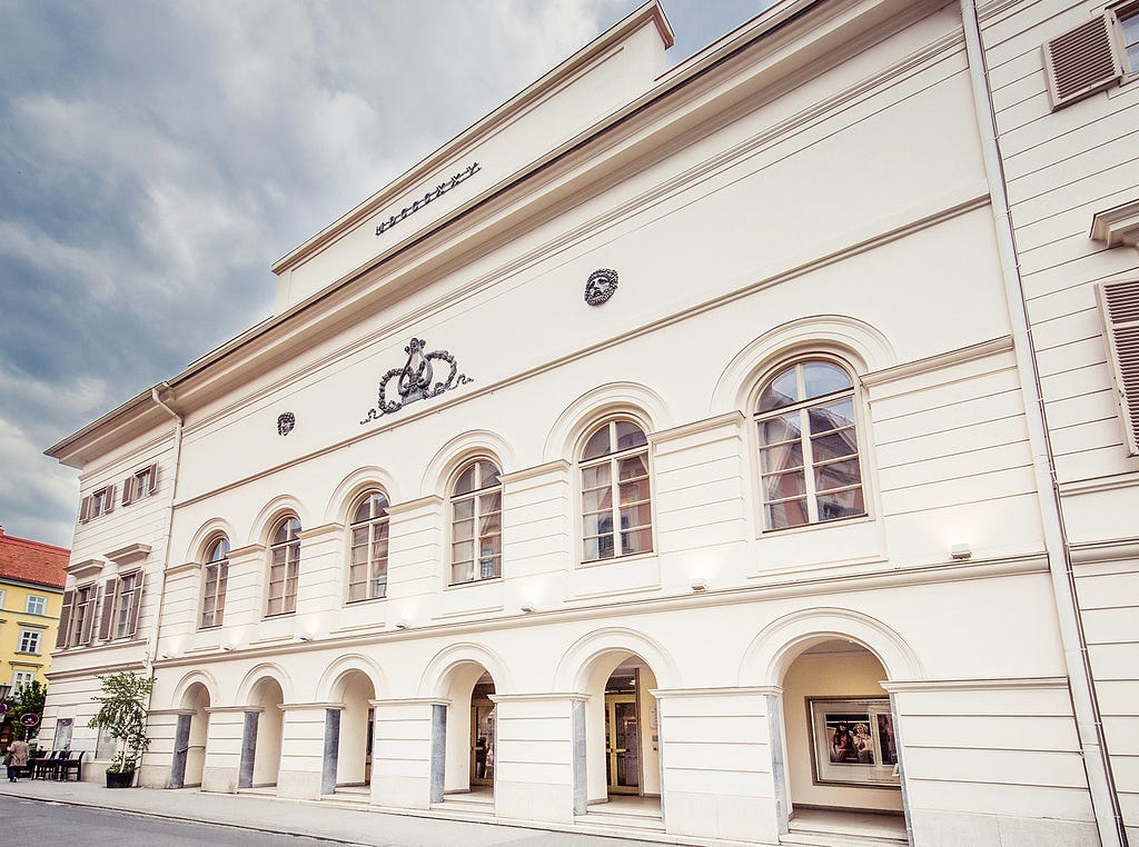 An imposing off-white building seen from a slanted angle.
