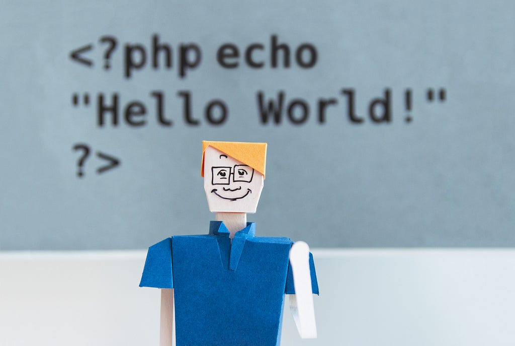 Paper person with code in the background displaying “Hello World!”