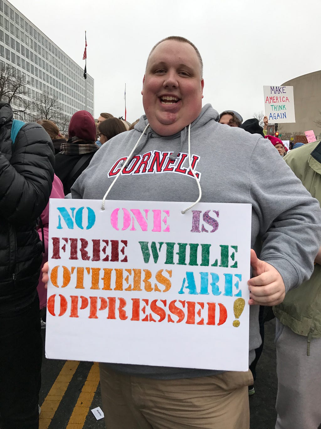 Man in Cornell sweatshirt holding a sign that says no on is free while others are oppressed.