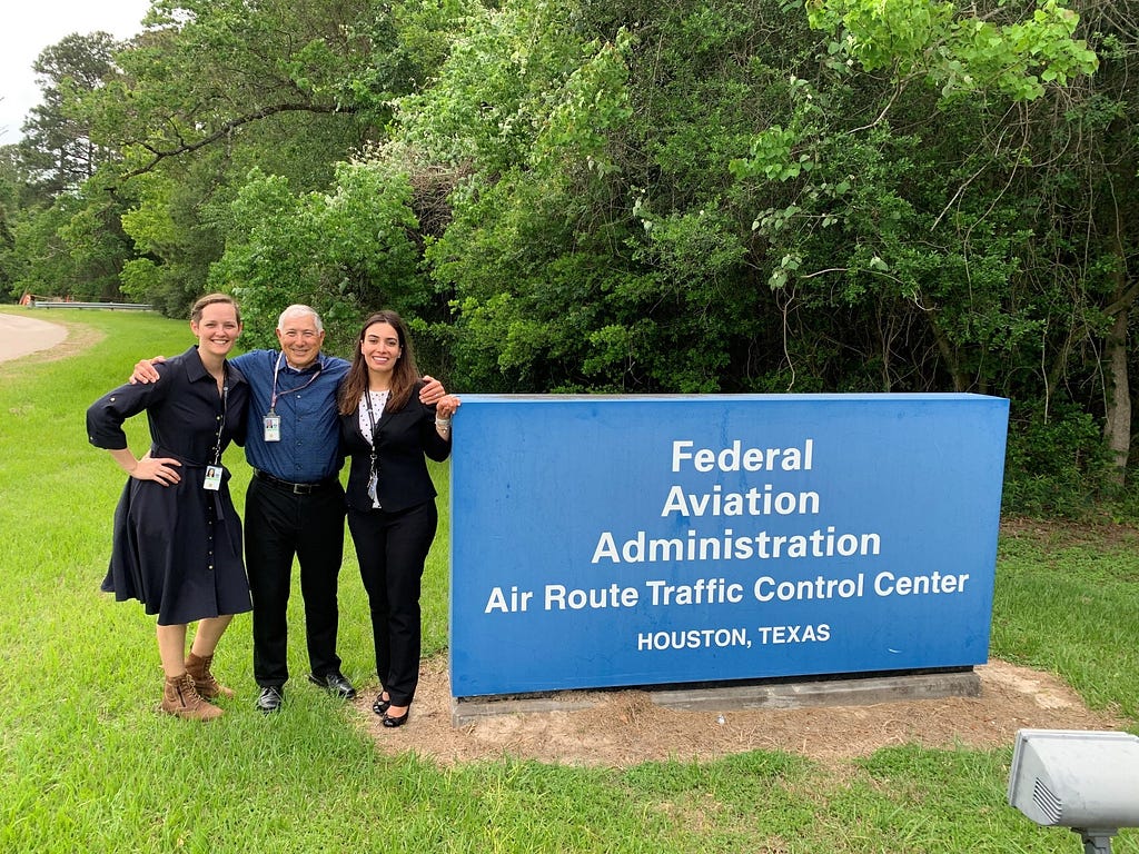 Rana posing with two colleagues next to the sign for the FAA Air Route Traffic Control Center in Houston, Texas.