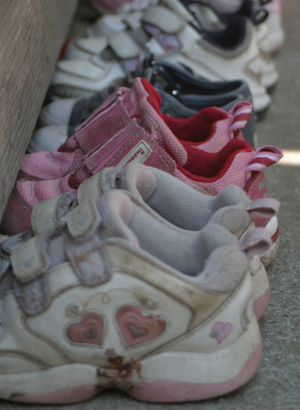 Five pairs of children’s shoes stand empty in a line.