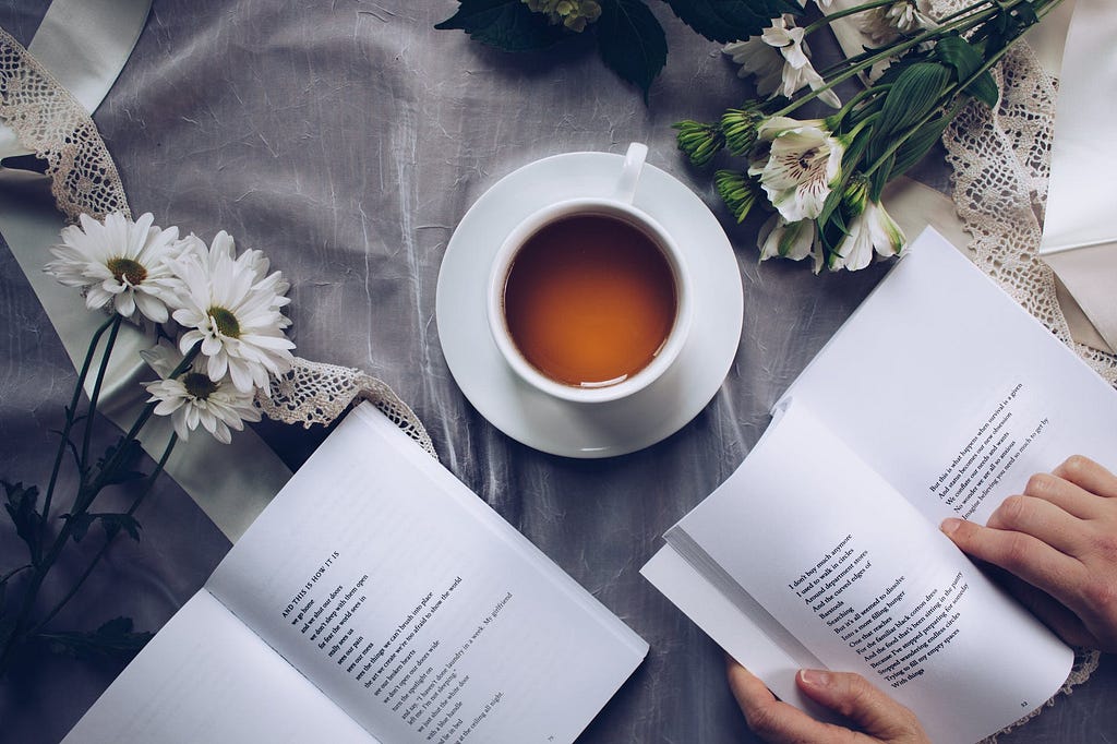 Picture of a cup of coffee, flowers and books.