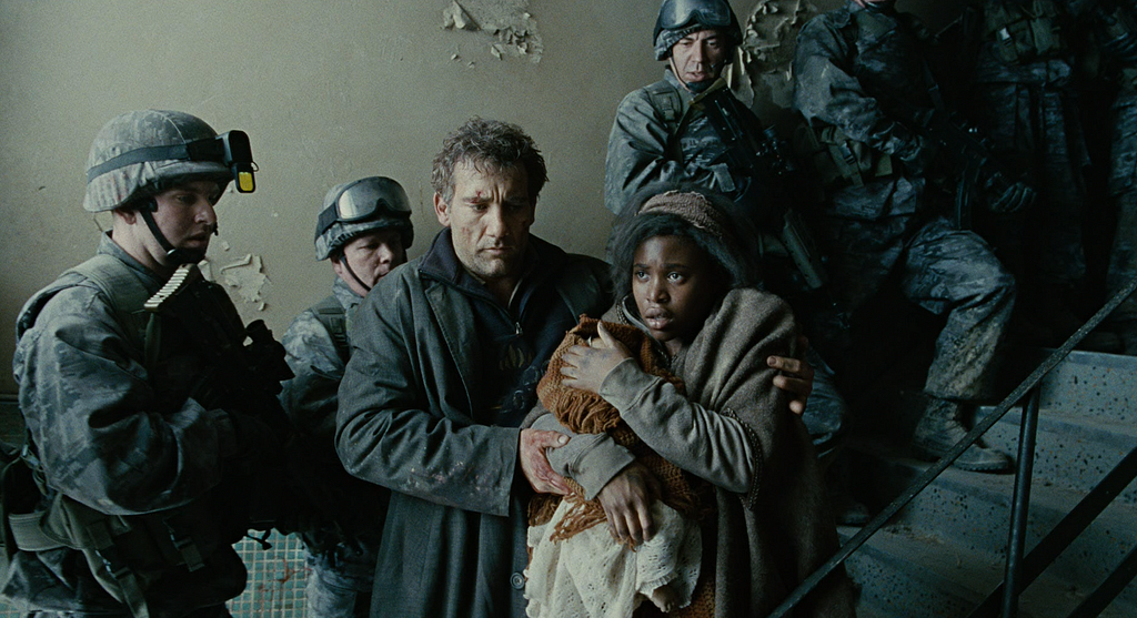 Clive Owen leads a woman with a baby through a group of soldiers in Children of Men