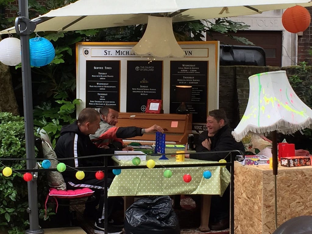 Three men are sat at a table playing connect 4.