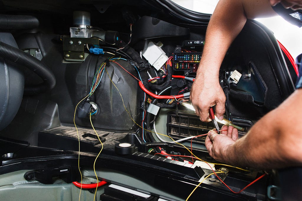 A mechanic performing the auto electrical service on a car