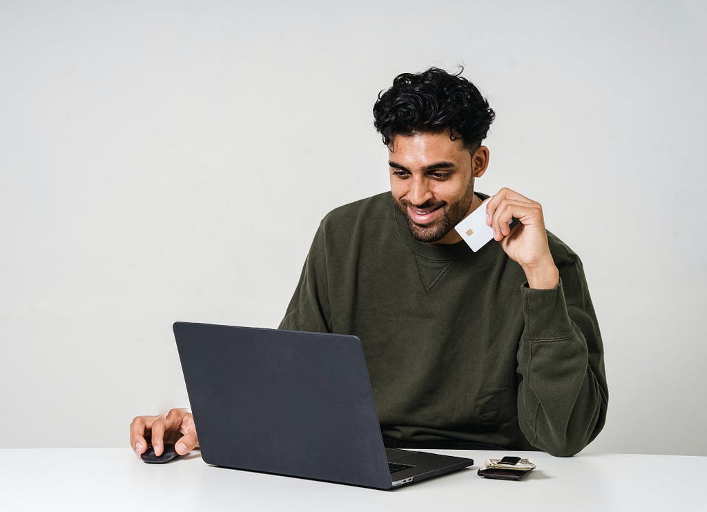 Man sitting at a laptop holding a credit card.