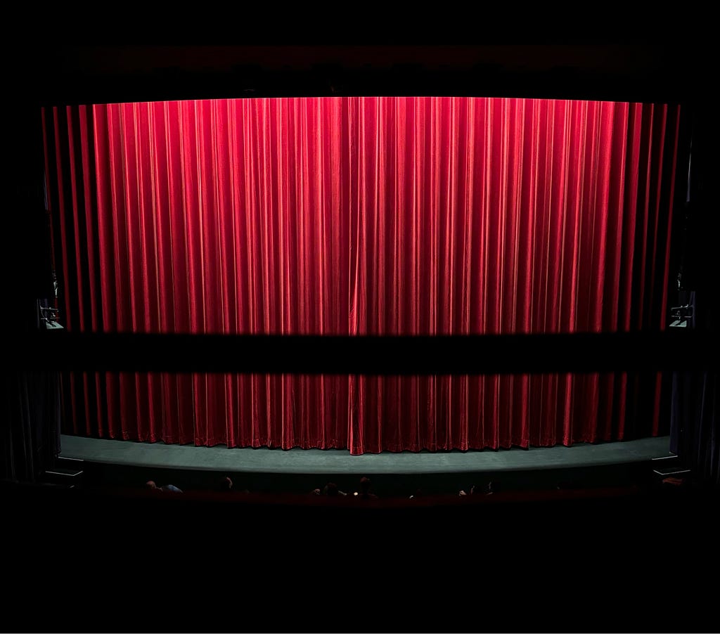 A closed red curtain before the showing of a film.