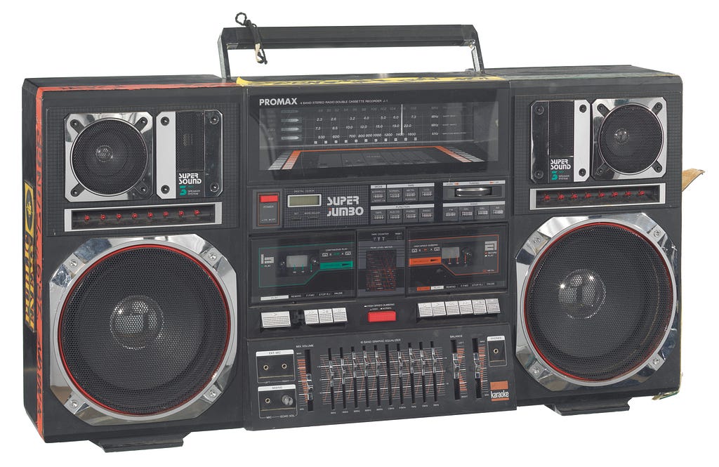 A Promax Super Jumbo boombox (2014.270.2.1a) used as a prop by the character Radio Raheem in the Spike Lee directed picture, “Do the Right Thing”. The boombox includes a dual audio casette tape deck, an equilizer section, radio dial, colored light display, and a pair each of 8" subwoofers, midranges, and tweeters. There are sections of red, yellow, and green electical tape with black ink text on the sides and top of the player. There are also rectangular black, green, and yellow “Public Enemy” s