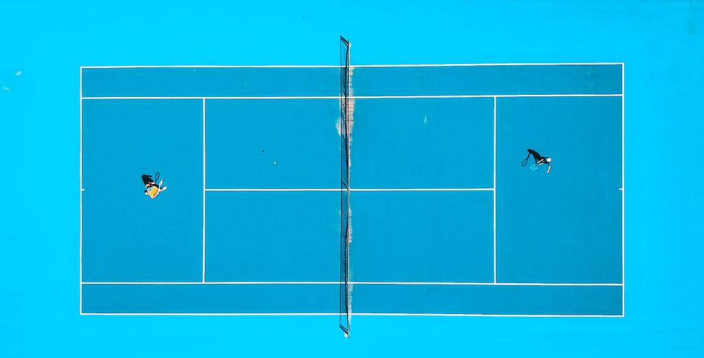 Aerial shot of two tennis players on bright saturated tennis court