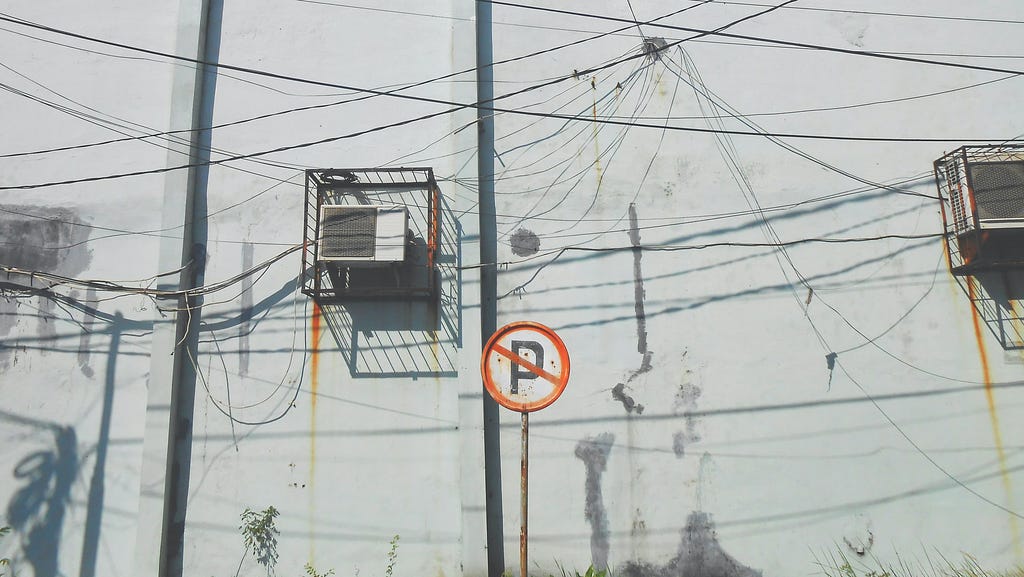 Very messy electrical wiring in urban environment, with cables running in every direction.