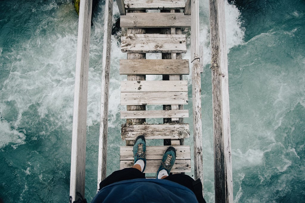 A person standing on a wooden bridge over a body of water