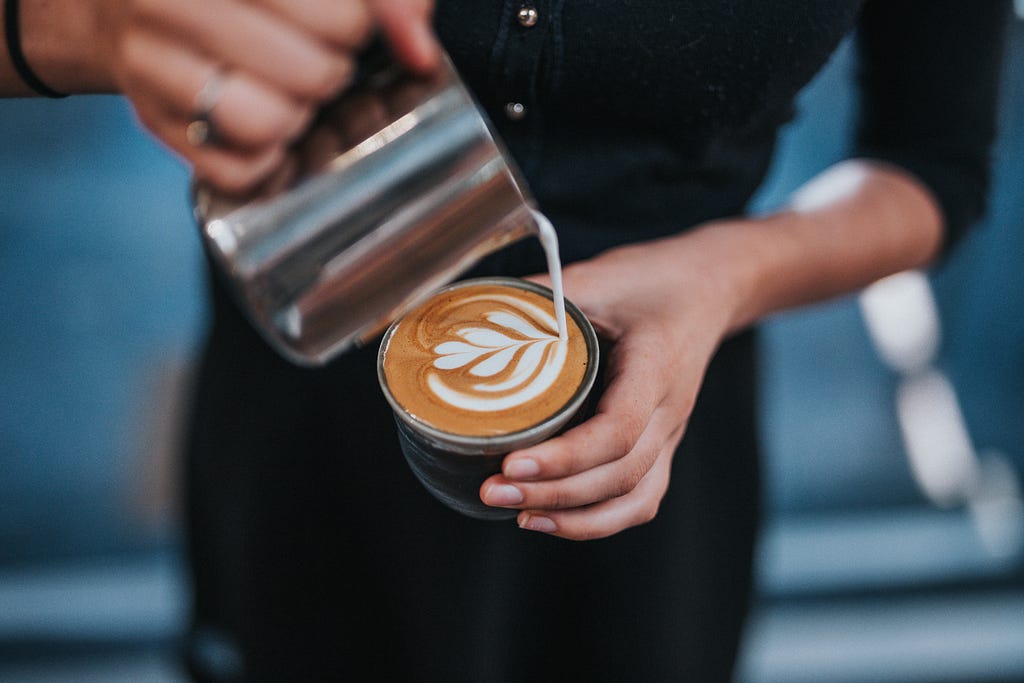 An image of a barista pouring coffee