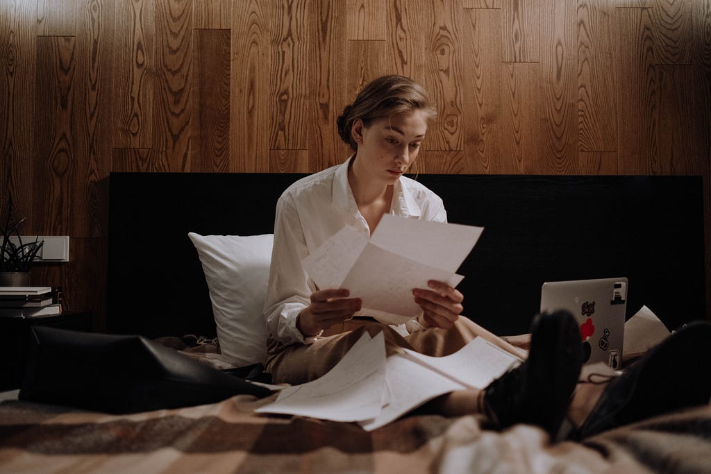 A woman reviews some documents in bed.