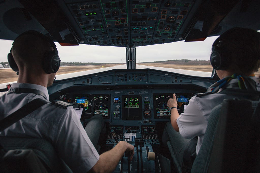 A co-pilot and captain in the cockpit of a commercial plane facing the runway