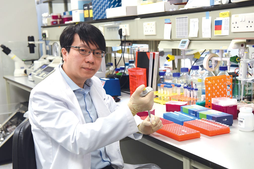 Dr Tommy Lam Tsan-yuk holding test tubes at a wet lab in The University of Hong Kong.