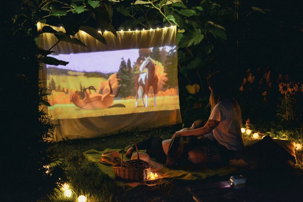 A mom and a kid watching a movie on an outdoor screen