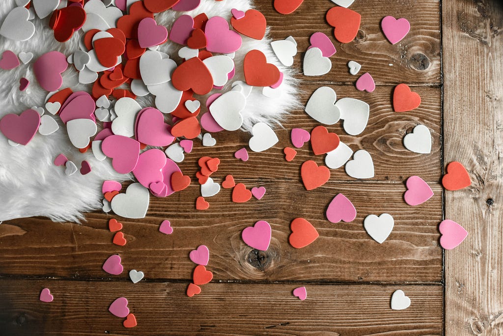 Heart confetti of different colours on wooden floor