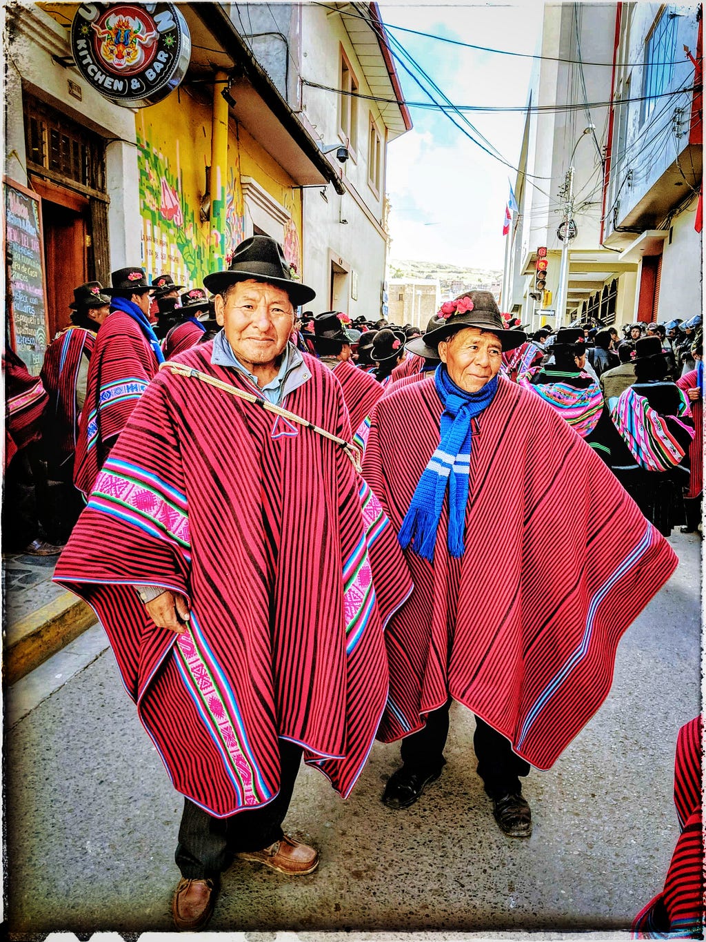 Two Indigenous Peruvian men in traditional panchos pose for the camera at a protest.