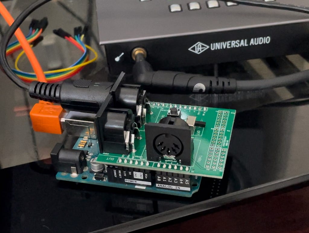 The Arduino UNO with the midi shield attached on top and USB and MIDI cables connected.