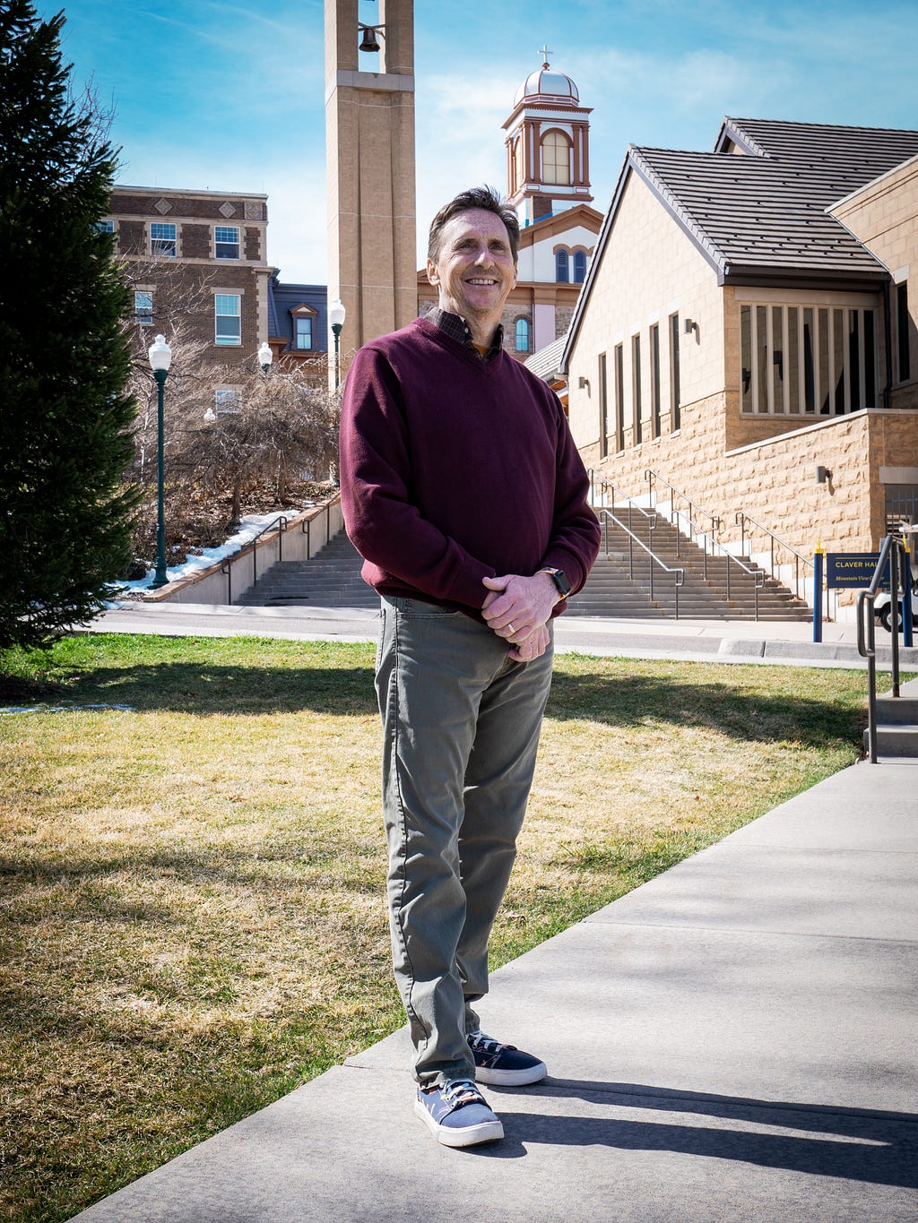 Justin Regan poses behind the Regis University Chapel and Main Hall