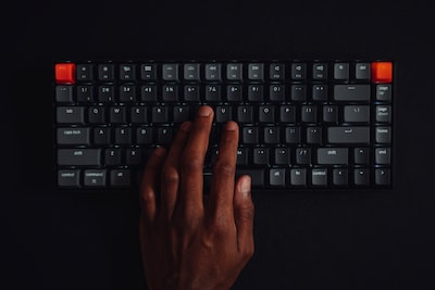 A hand typing on a black mechanical keyboard for coding