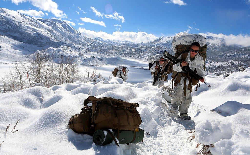 American soldierrs in winter gear near the top of a mountain.