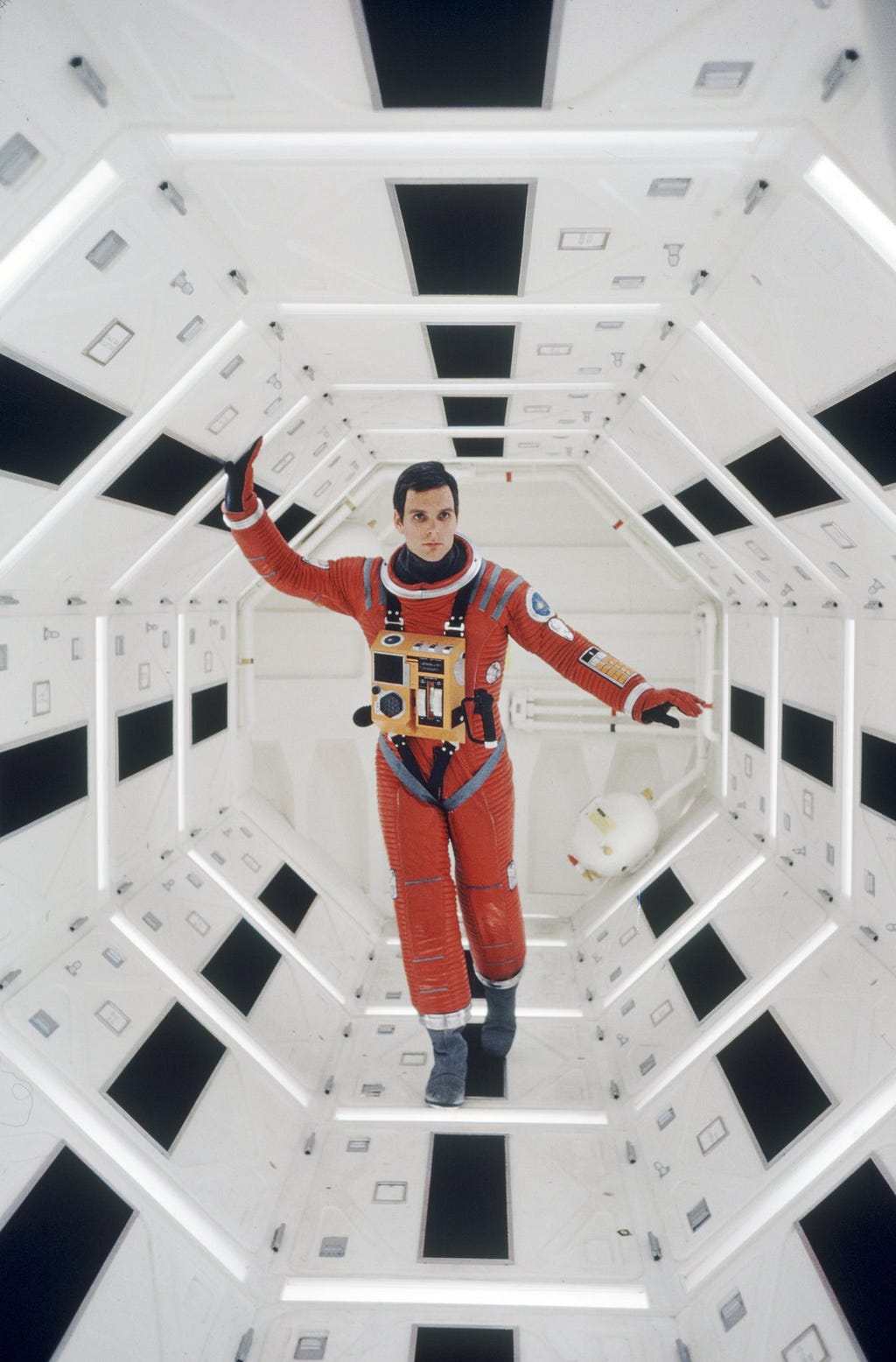 A picture from the movie 2001: A Space Odyssey. A astronaut floats in a futuristic white corridor while on a spaceship.