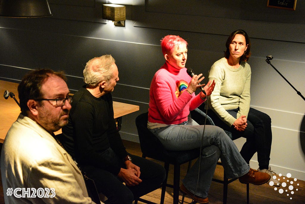 Podiumsdiskussion zum Thema Ethik und CRO in der Bar des Hotel Opduin auf der niederländischen Insel Texel. Moderator Charles Meadon (links) schaut ins Publikum, während ich (Mitte) ins Mikrofon spreche. Kaat Declerck sitzt auf dem Barhocker rechts und schaut und hört mir zu. Martin van Kranenburg sitzt auf dem Barhocker zwischen Charles und mir und schaut mich an.