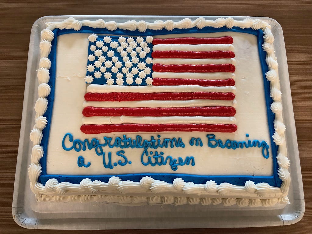 Large cake decorated with a U.S. flag in frosting, and says “Congratulations on becoming a U.S. citizen”