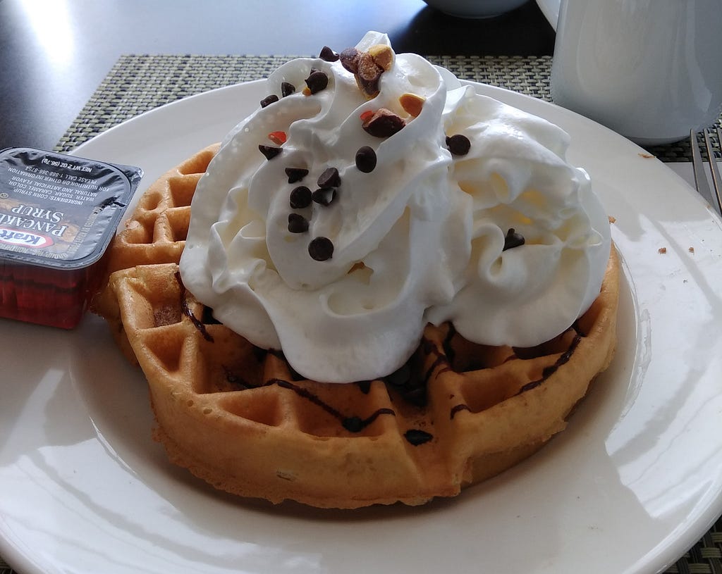 Belgian waffles with whipped cream, nuts, chocolate chips and chocolate syrup.