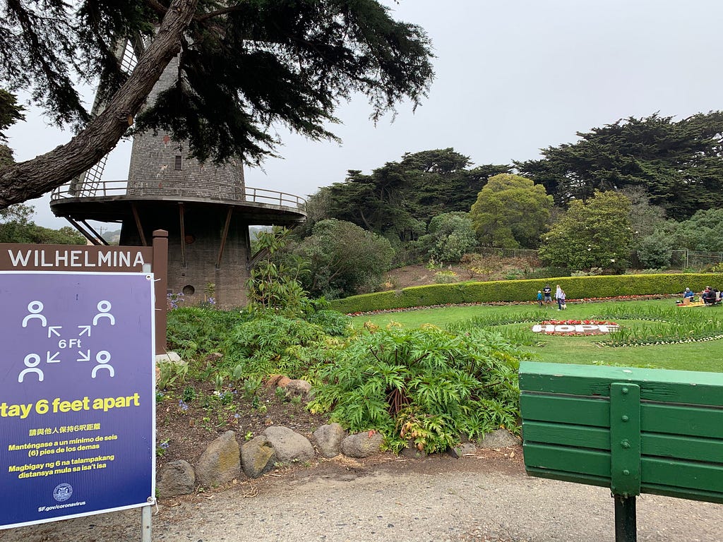 San Francisco Wilhelmina park. Photo depicts windmill, social distance sign and a garden that spells the word “hope.”