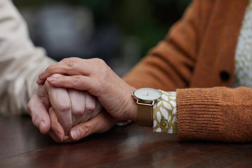 Two people hold hands in a pose suggesting empathy and support