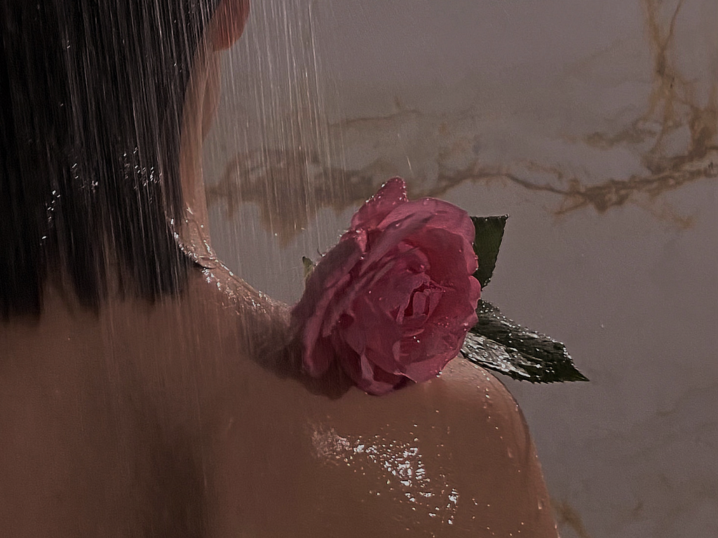 a metaphorical image of a girl standing in a shower with a rose on her shoulder