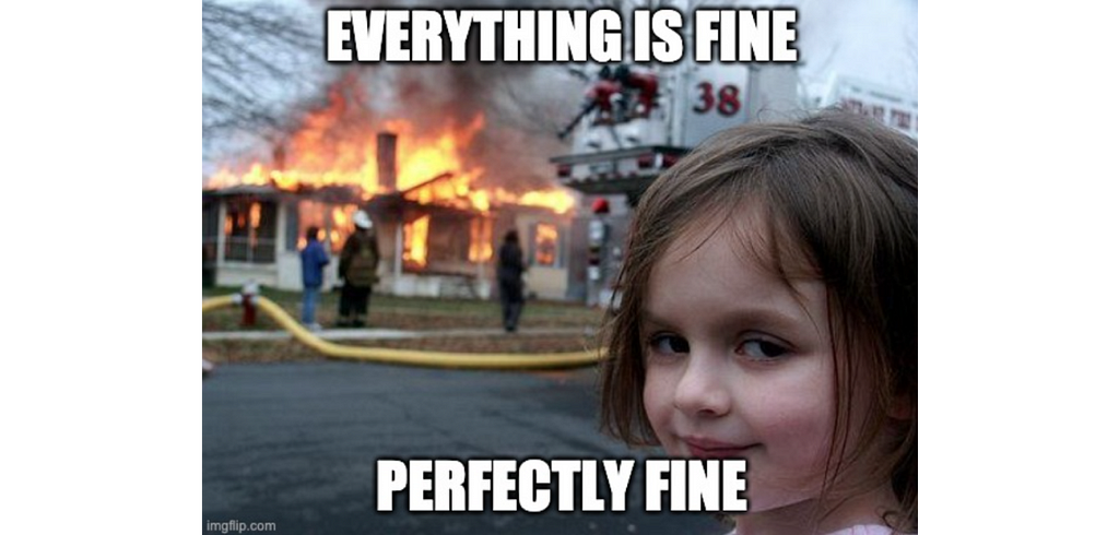 Disaster girl meme. Girl in the foreground laughing, house in the background on fire. Text: “Everything is fine, perfectly fine”.