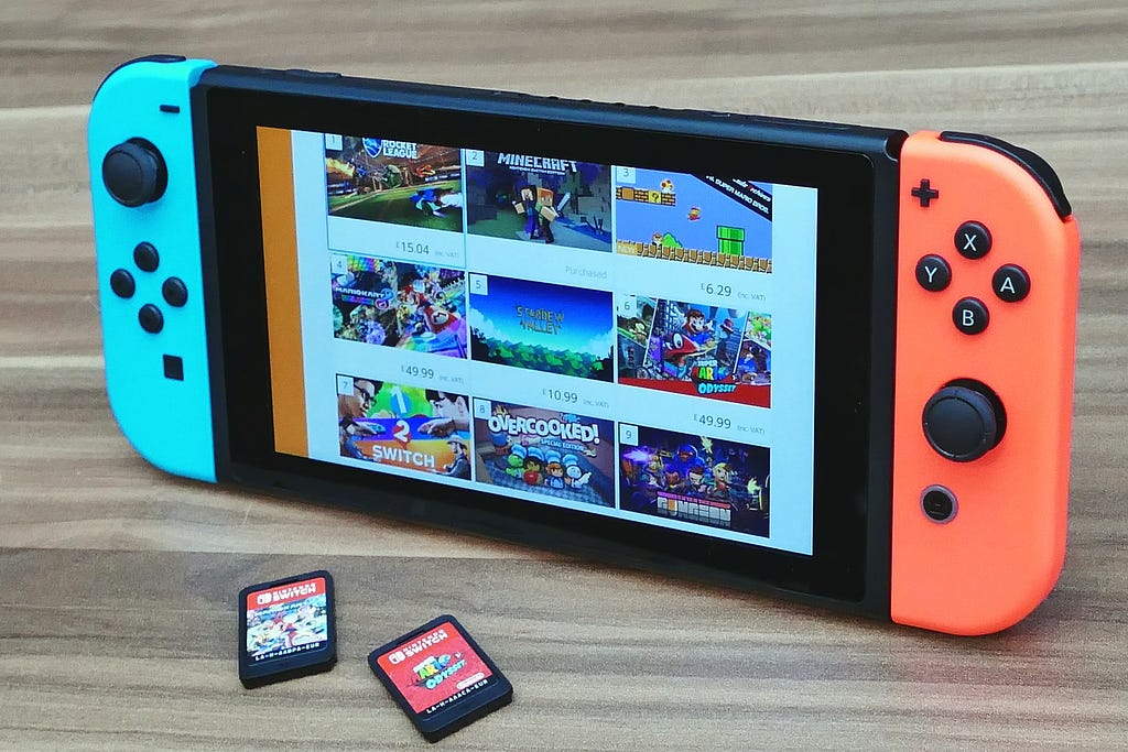 A Nintendo Switch turned on to feature an assortment of games, including two cartridges.