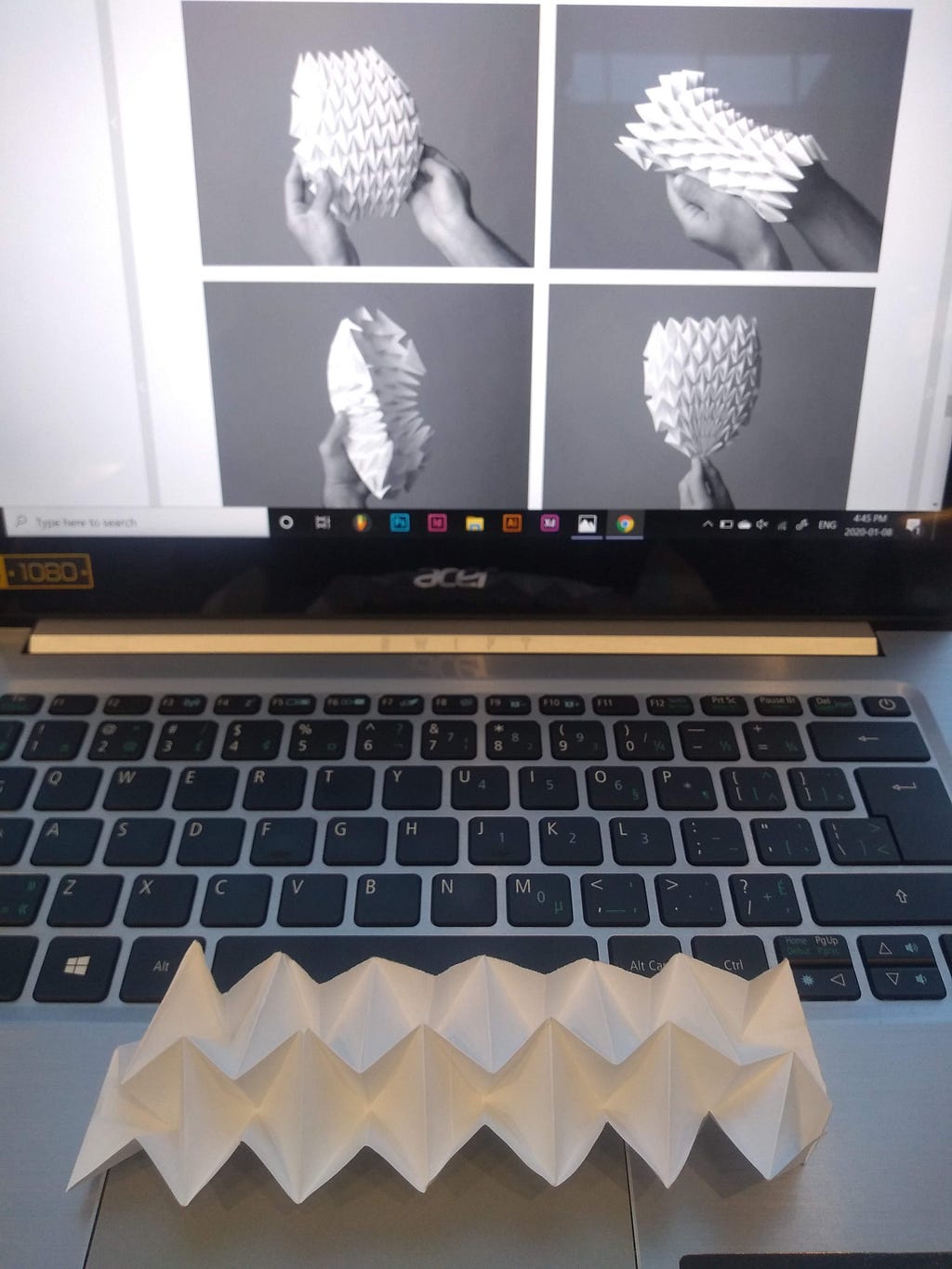 A laptop showing an intricate origami fold, and an actual origami sample