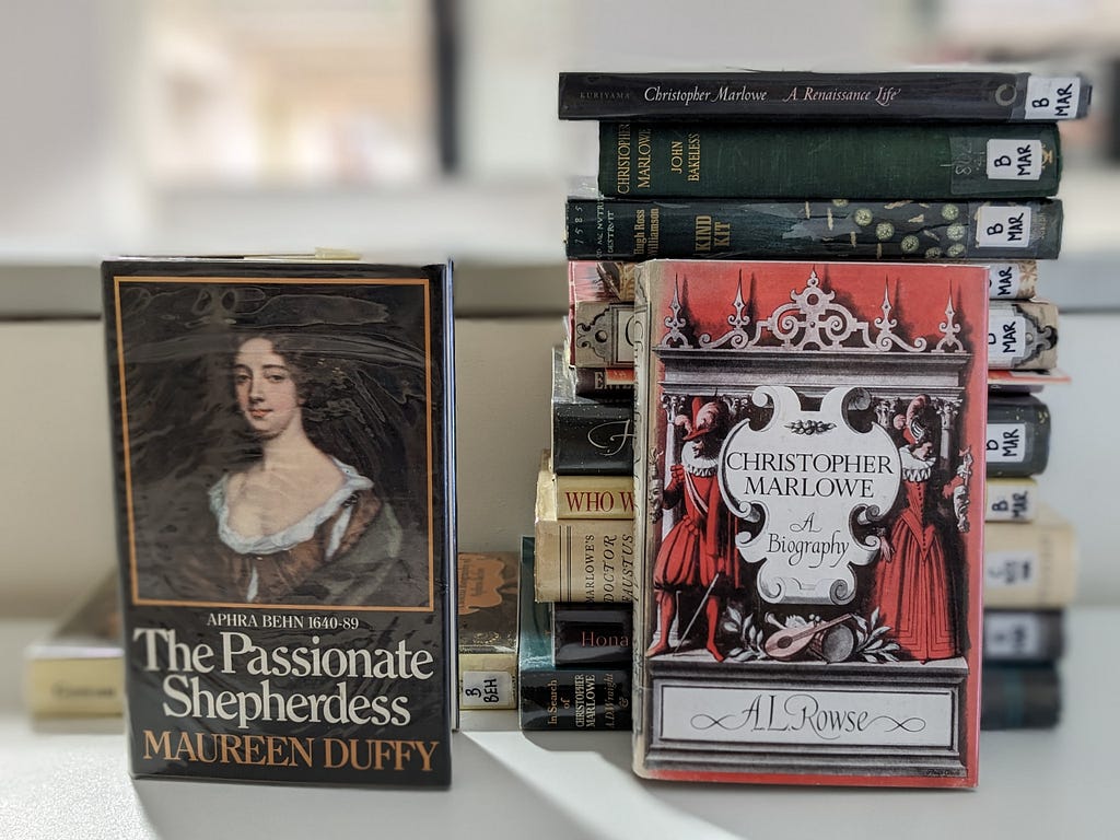 Two books about Aphra Behn next to a dozen books about Christopher Marlowe taken at the Canterbury Library.