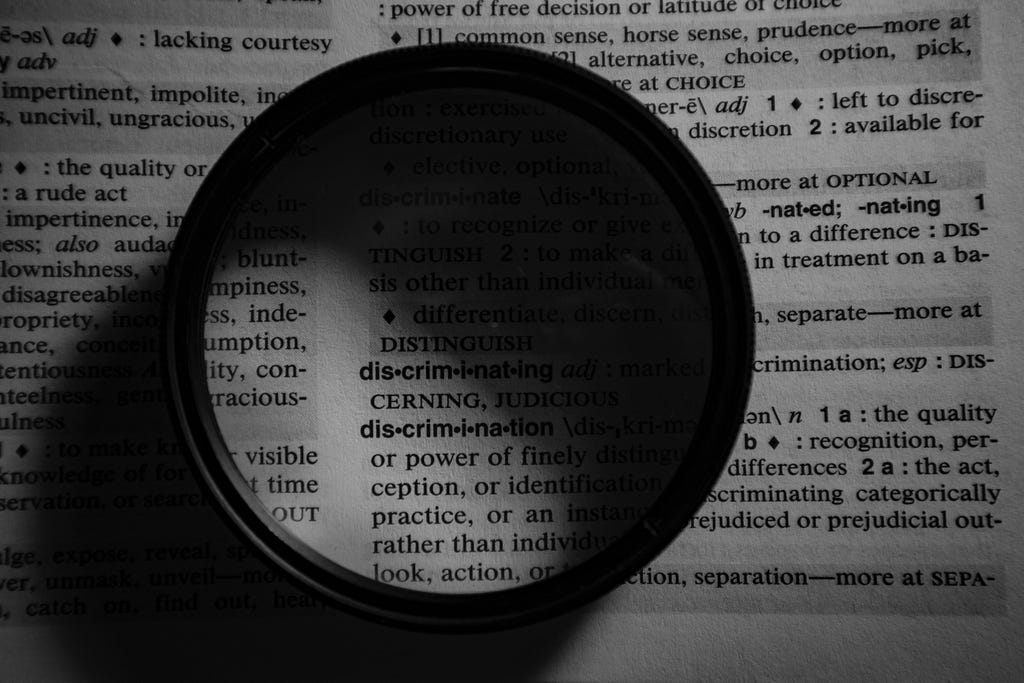 a page from the dictionary with a magnifying glass on the word “discrimination”