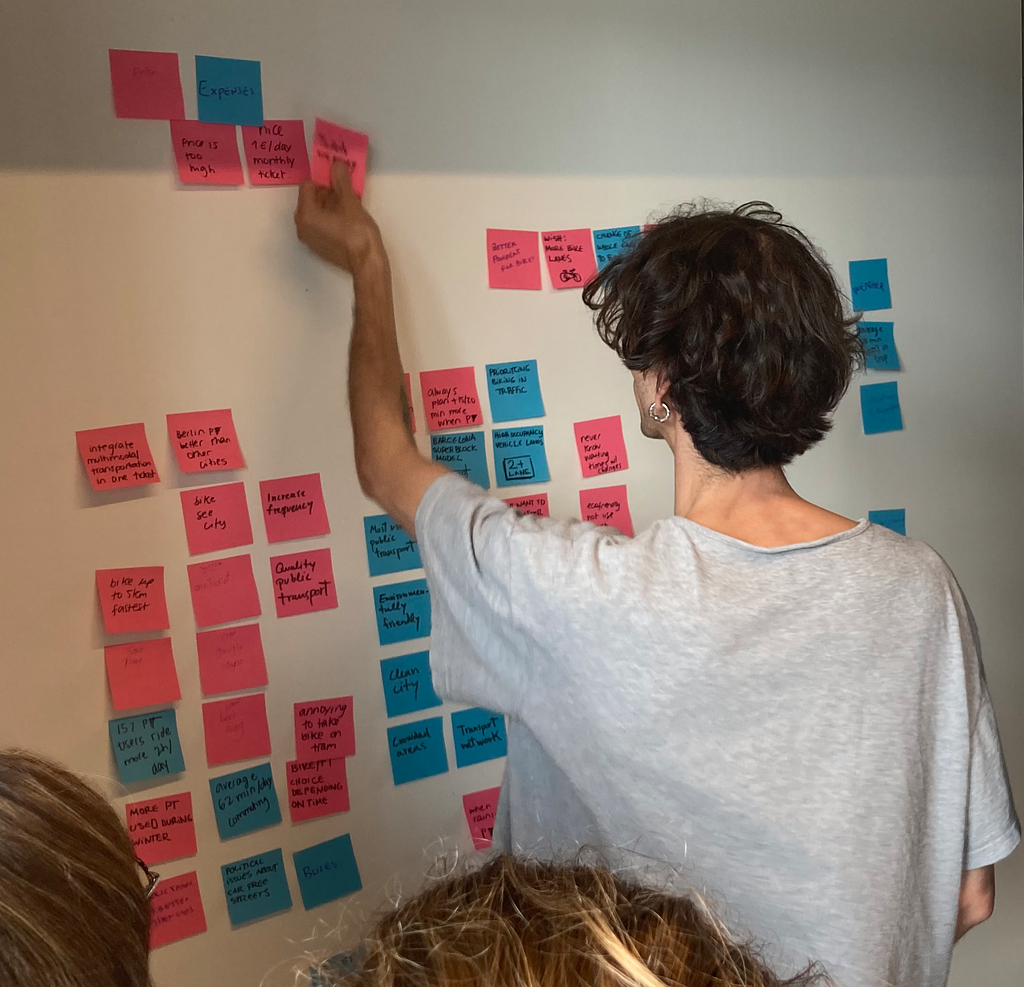 Person pairing sticky notes on a affinity diagram
