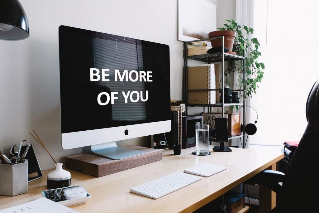Computer desk with “Be More of You” on computer screen