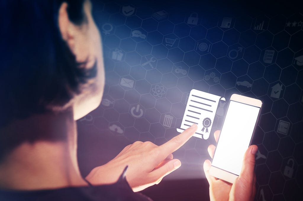 Woman holds a smartphone in hands and presses on the certificate (diploma) icon. Image Credit: SvetaZi on iStock.