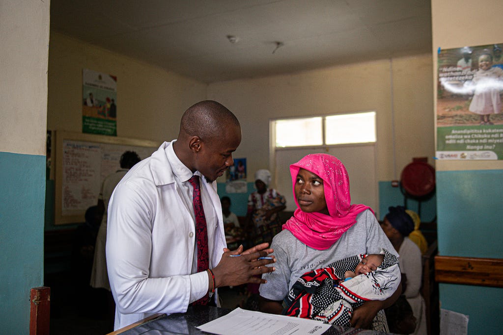 A doctor speaks with a mother holding a baby.