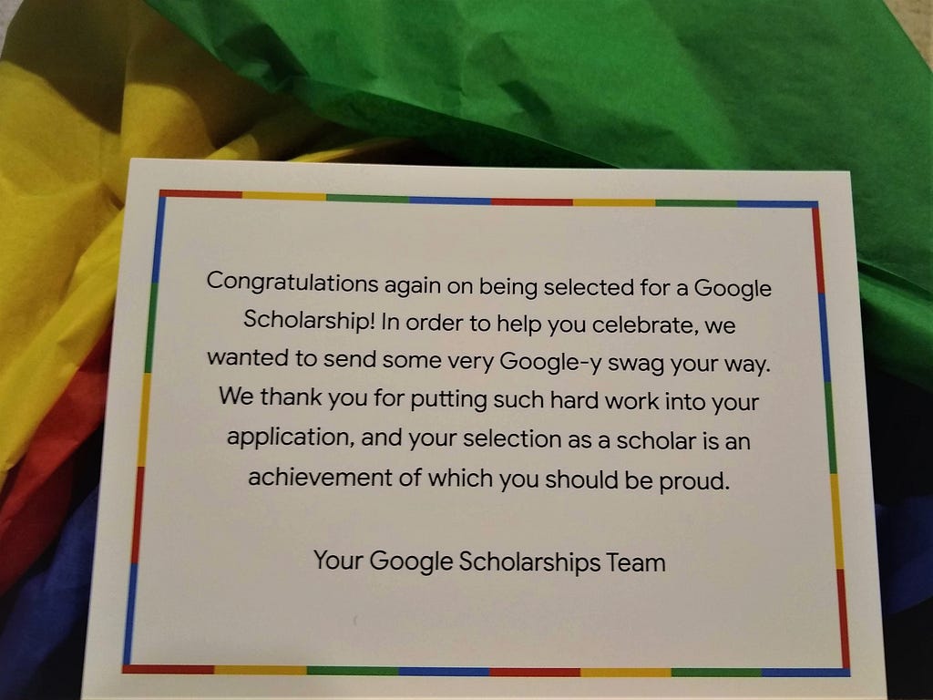 A Congratulations card from the Google team to Nandita , sitting on a bed of yellow, green, red and blue parchment paper.