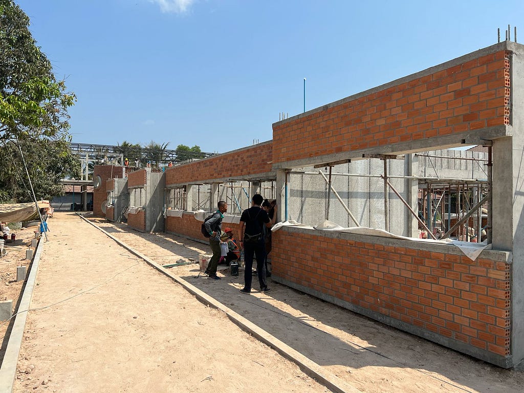 A building is under construction. There are some workers next to the building.