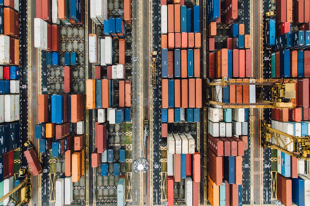 High traffic view of a ship yard showing many containers and coordination between them.
