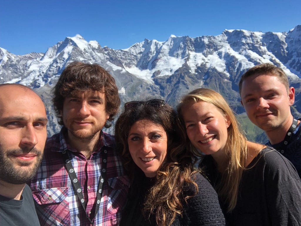 5 people standing in front of snowy mountains