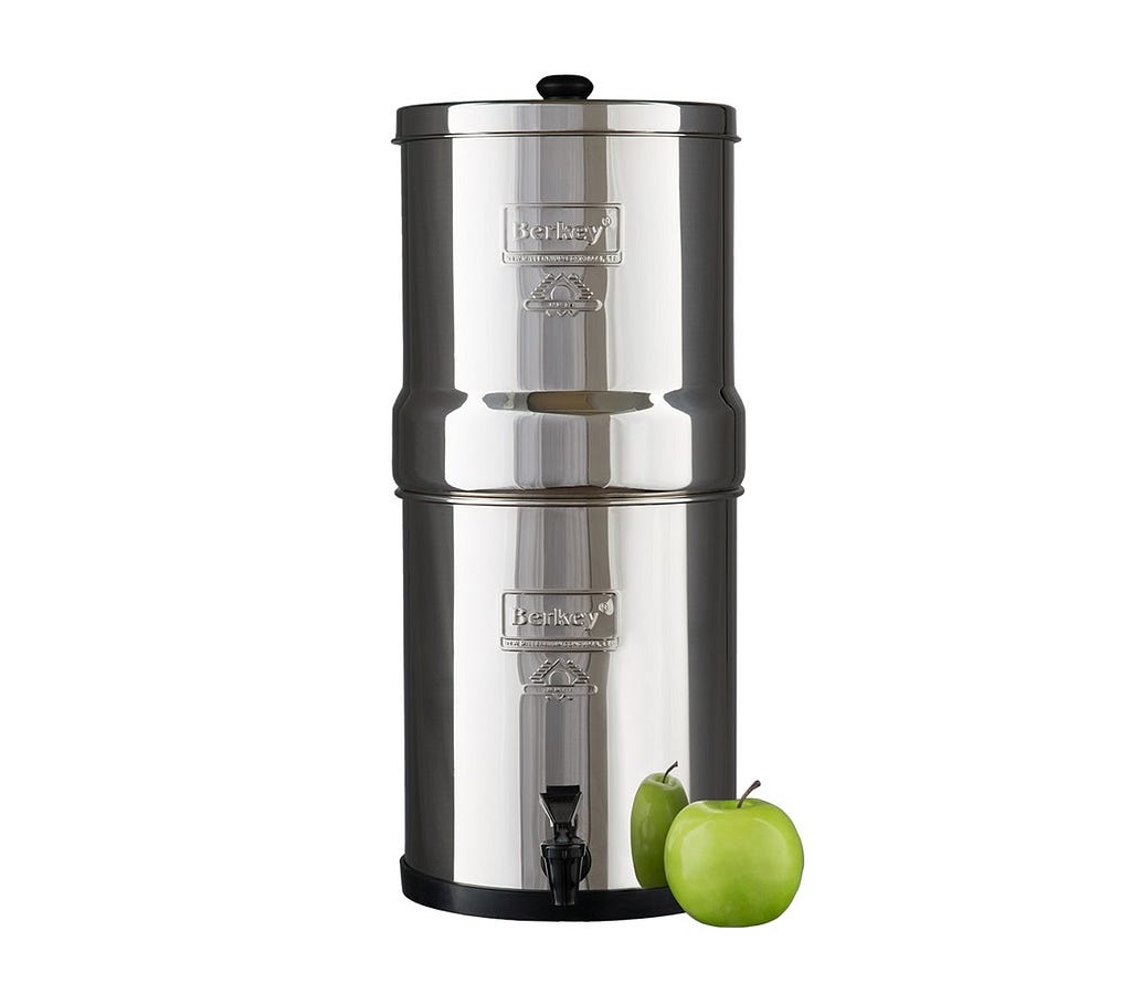 Round Stainless Steel Berkey Water Filtration System Tower with a green apple leaning against the right side