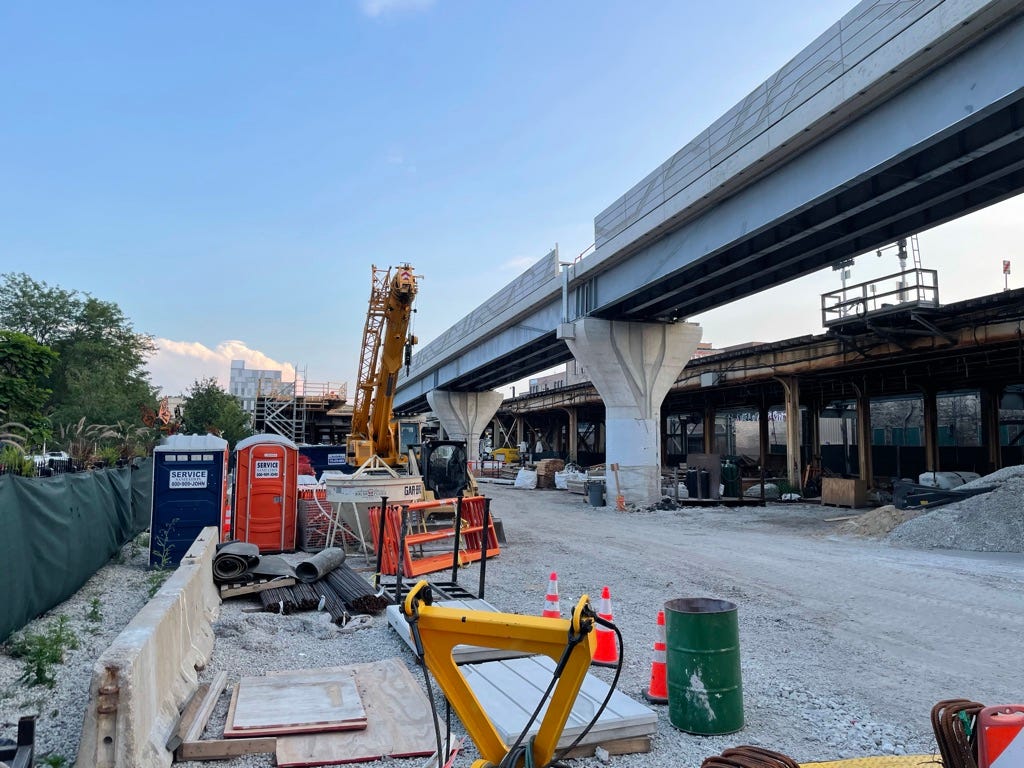photo of the Belmont Bypass flyover under construction in 2021, with construction equipment stored on a vacant lot in the foreground.